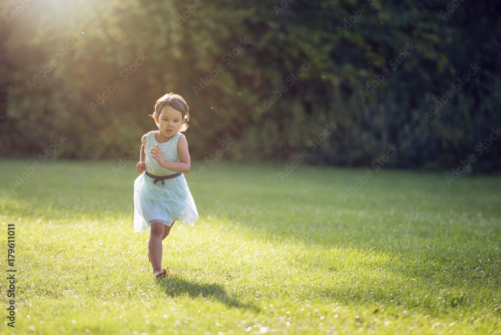 Little girl running in park with no shoes on grass Little girl running in park with no shoes on grass