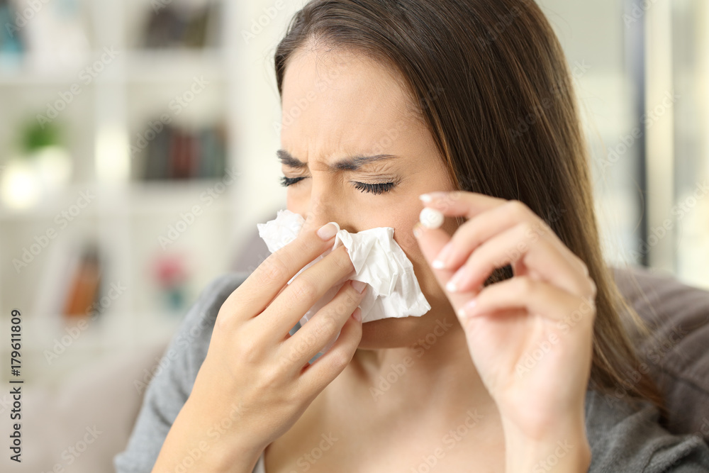 Woman coughing covering mouth with a tissue at home