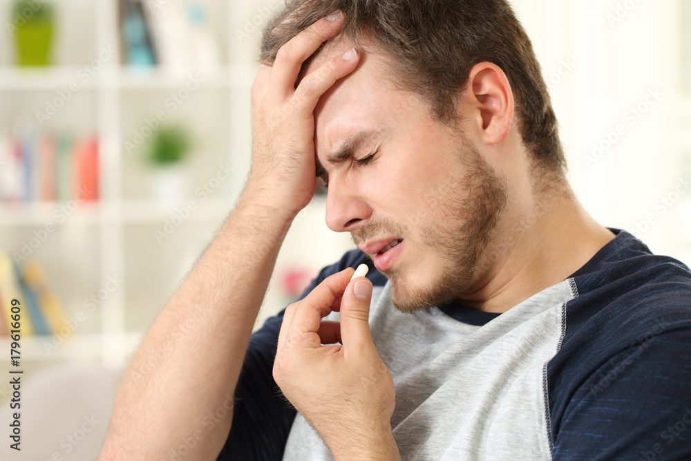 Man suffering headache taking a pill Man suffering headache taking a pill