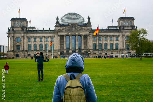 Young woman with backpack looking at Bundestag building in Berlin. Erasmus student, studying abroad and tourist concept.