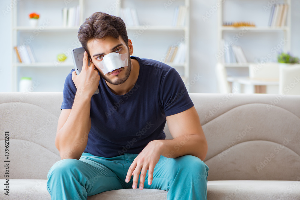 Obraz premium Young man recovering healing at home after plastic surgery nose
