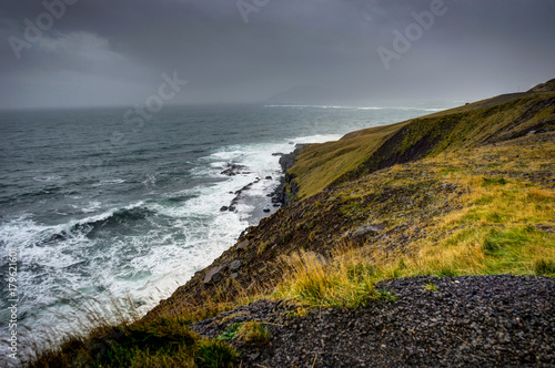 Atlantic Ocean in Iceland with clouds and mountains view grass f