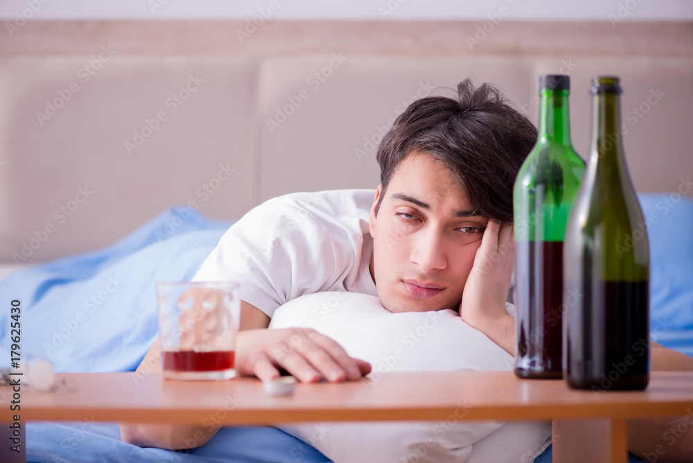 Man alcoholic drinking in bed going through break up depression Man alcoholic drinking in bed going through break up depression