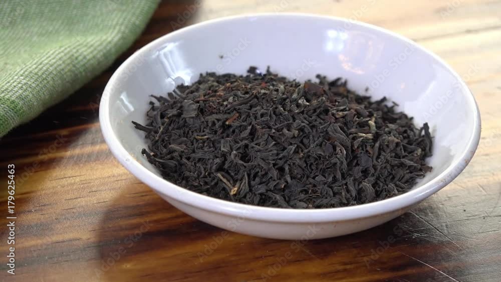 Whole leaf black tea falling into a dish, slow motion Whole leaf black tea falling into a dish, slow motion