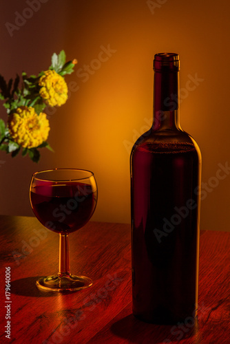 a bottle of wine with a glass and flowers