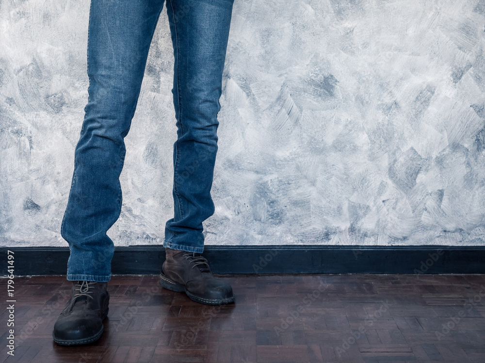 Close up of Man's legs in jeans and boots on wooden floor. Free space for text Close up of Man's legs in jeans and boots on wooden floor. Free space for text