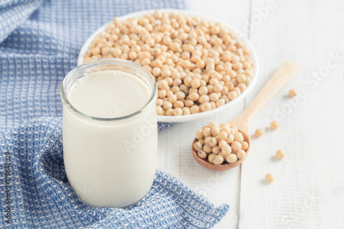 A glass of soy milk on a white wood floor with soybean as a background. © sorrapongs