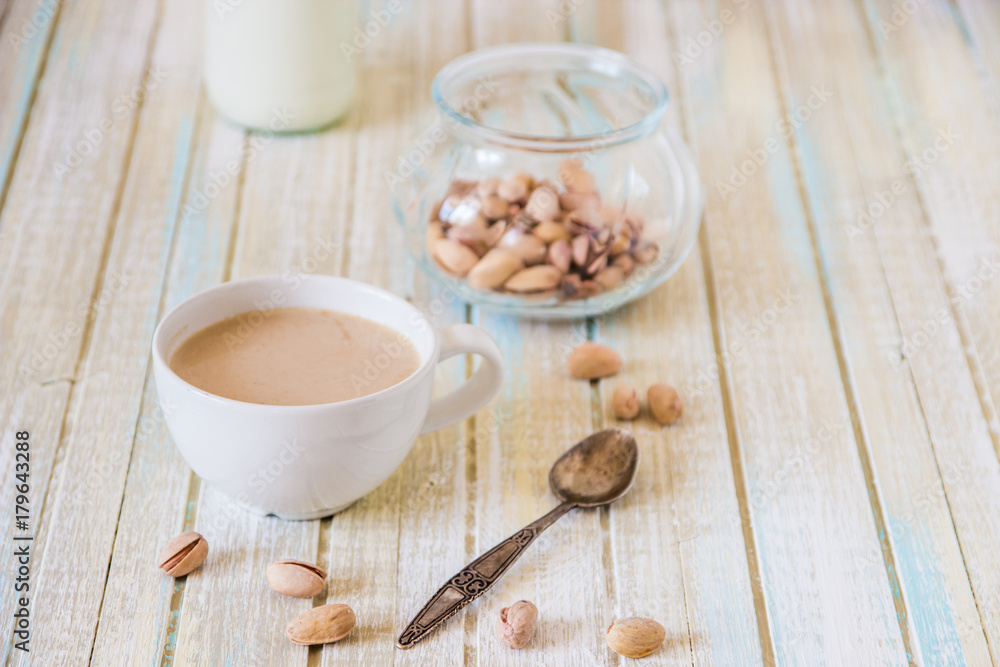 Coffee with milk and pistachios on wooden table Coffee with milk and pistachios on wooden table