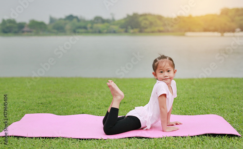 Asian child girl doing yoga in the public park.
