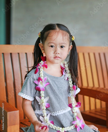 Portrait of asian girl sitting on the wooden chair with welcome orchids garland. photo