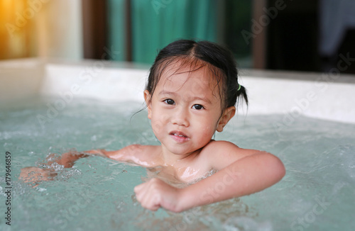 Little girl playing water in the bathtub.