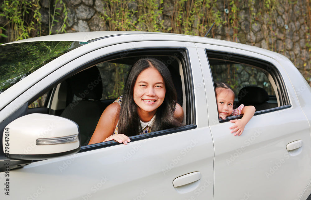 Happy young woman and her little child girl sitting in a car and look out from windows. Family travel concept. Happy young woman and her little child girl sitting in a car and look out from windows. Family travel concept.