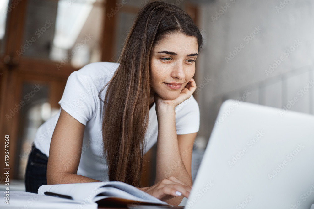 Happy young woman using laptop to scroll through tons of social media posts and photos smiling. Happy young woman using laptop to scroll through tons of social media posts and photos smiling.