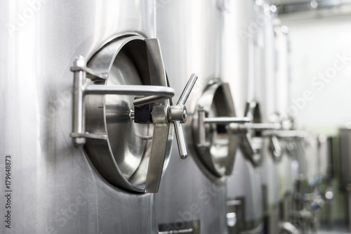 A lot of stainless steel tanks with large round hatches, modern beverage production.