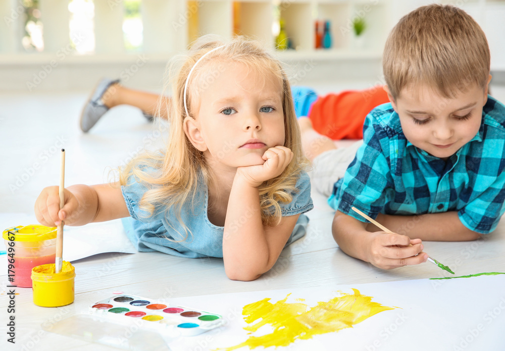 Fototapeta premium Children lying on floor in light room and painting