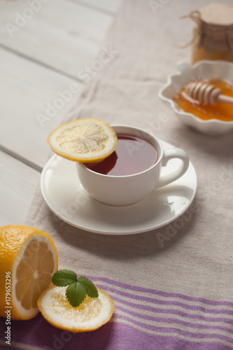 Breakfast of tea, lemon and honey on white wooden background. vertical