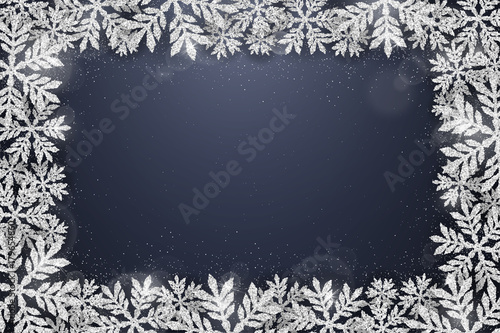 Merry Christmas and Happy New Year greeting card with silver glittering snowflakes frame on dark blue background