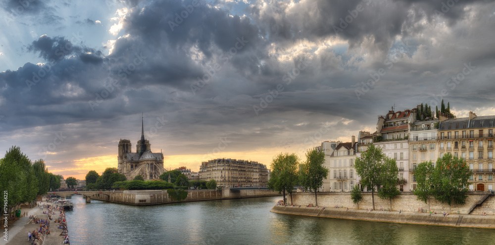 Notre Dame cathedral in Paris, France, at dusk. Scenic skyline with dramatic clouds. Panorama view.