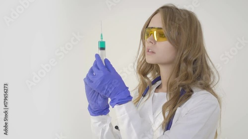 Young woman doctor holding syringe on white background photo