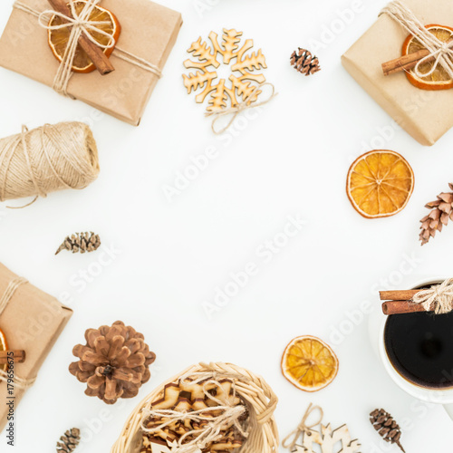Frame of Christmas or New Year decoration, paper gift box, coffee mug and pine cones on white background. Flat lay, top view