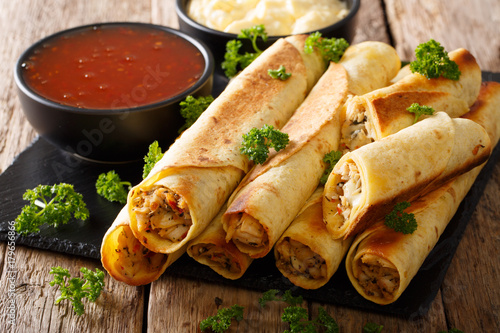 Tasty taquitos with chicken and two sauces close-up. horizontal photo