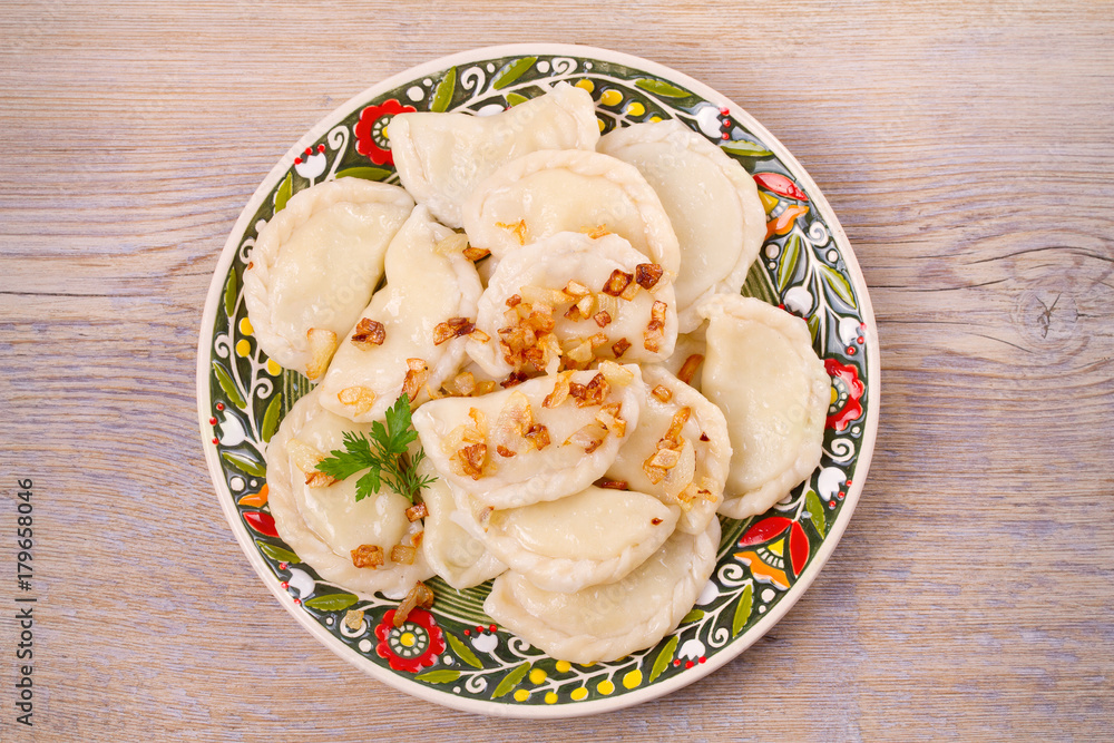 Dumplings, filled with potato and served with salty caramelized onion. Varenyky, vareniki, pierogi, pyrohy - popular dish in East Europe. View from above, top studio shot, horizontal