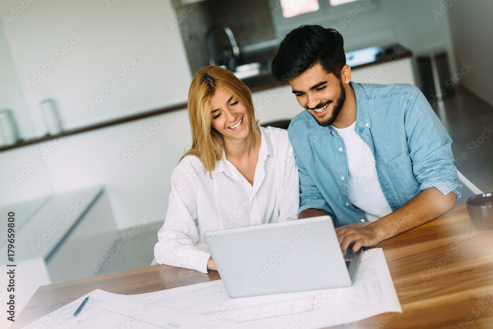 Handsome young man and attractive woman working on laptop