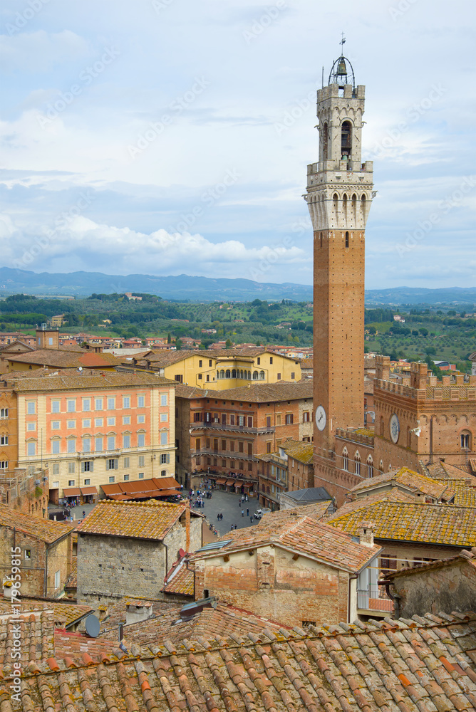 Torre del Mangia tower over the roofs of Siena. Italy