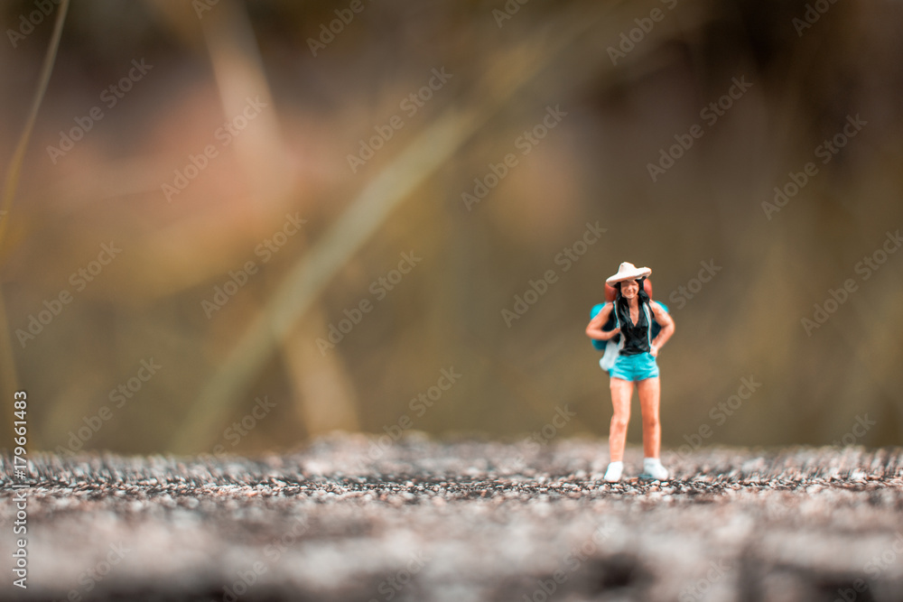 Miniature Backpacker standing on the concrete wall with natural background Miniature Backpacker standing on the concrete wall with natural background