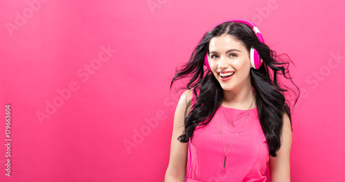 Happy young woman with headphones on a solid background