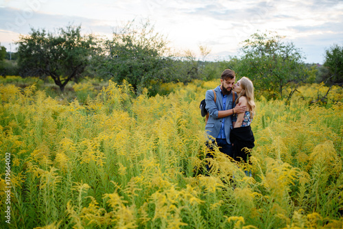 Young couple in love dressed in country style standing on field of flowers © vitleo