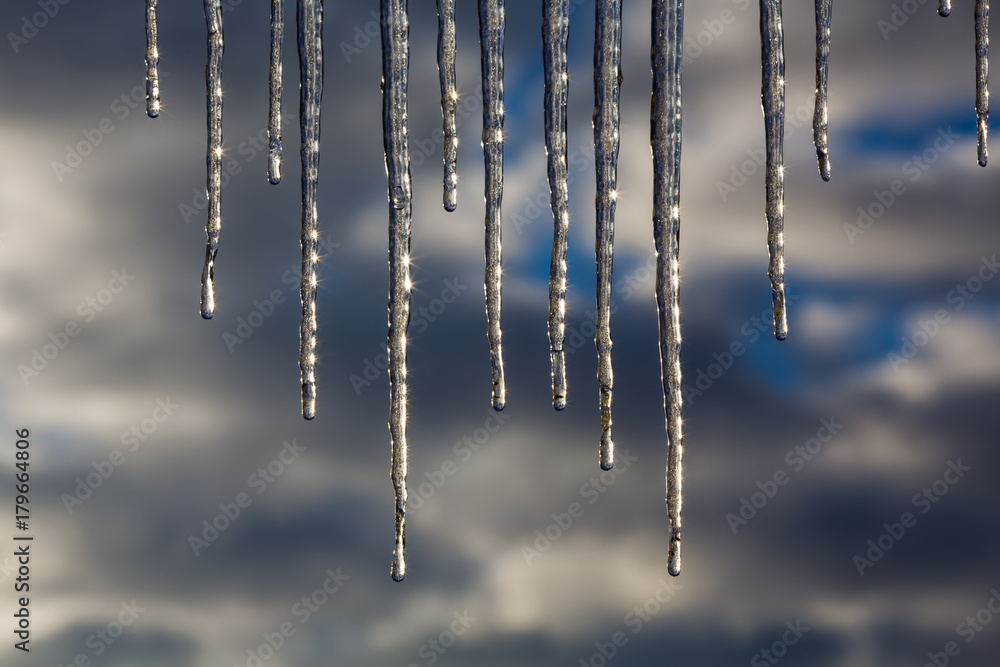 Winter ice icicles against the background of gray clouds Winter ice icicles against the background of gray clouds