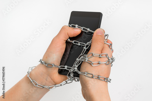 Chain ties together hands and smartphone - addiction concept