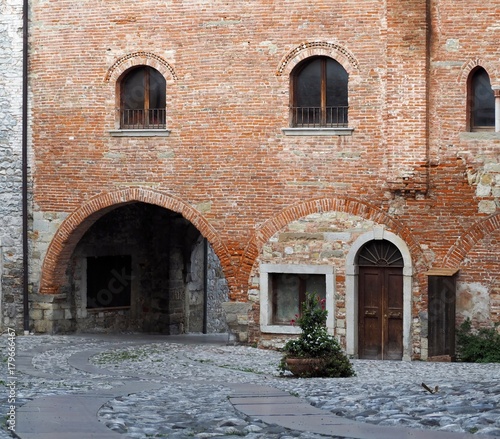 Fototapeta Naklejka Na Ścianę i Meble -  Medieval street arch under an ancient brick wall of a building facade in the town of Cividale del Friuli, now in italy