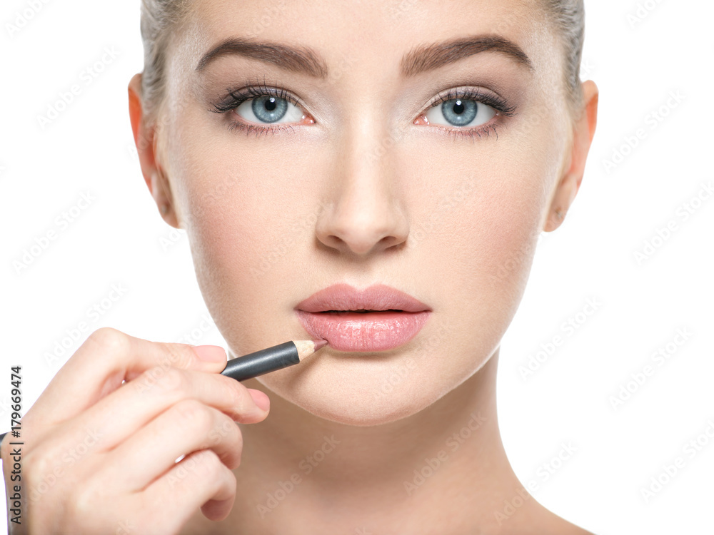 Woman apply lipstick with cosmetic pencil on the lips Woman apply lipstick with cosmetic pencil on the lips