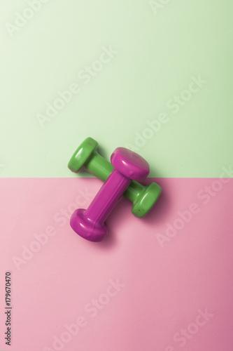 two dumbbell on the color(green, pink) paper background.
