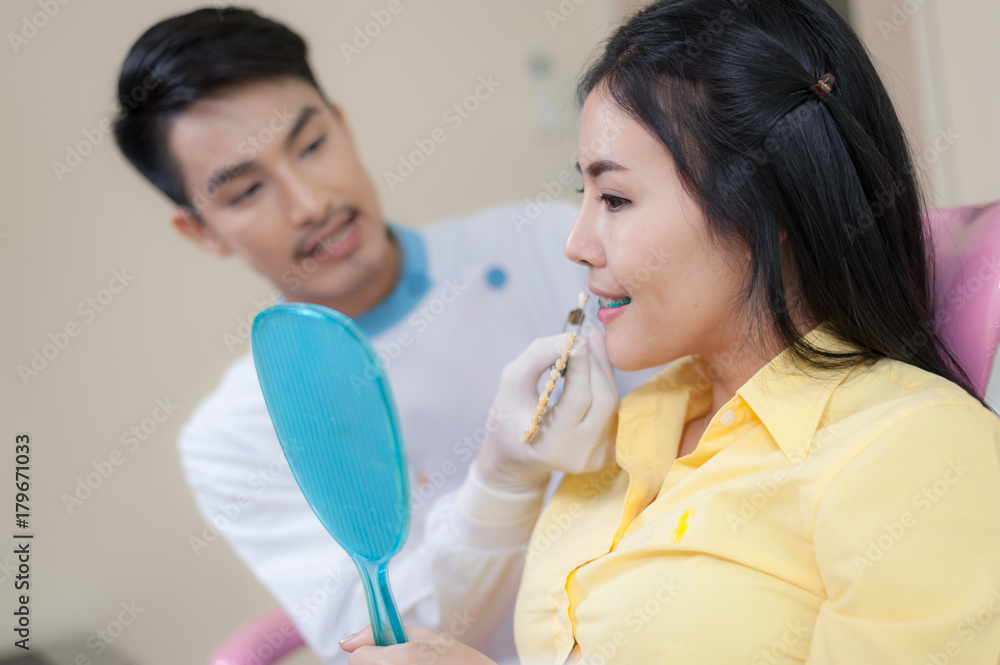 Male dentist explain about dental crown to female patient while doing dental checkup in clinic. Oral care and maintenance with expert concept. Male dentist explain about dental crown to female patient while doing dental checkup in clinic. Oral care and maintenance with expert concept.
