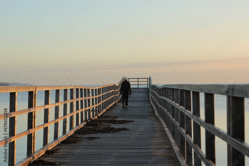 athletic old senior with grey hair and dumbbells walk along a pier