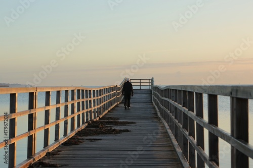 athletic old senior with grey hair and dumbbells walk along a pier