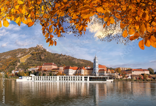 DUERNSTEIN CASTLE AND VILLAGE WITH BOAT ON DANUBE RIVER DURING AUTUMN TIME IN AUSTRIA