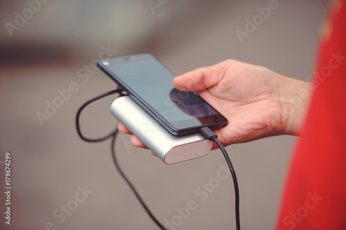 the man is holding the phone and the charger. Powerbank and smartphone in hand. Power-saving device power bank smartphone