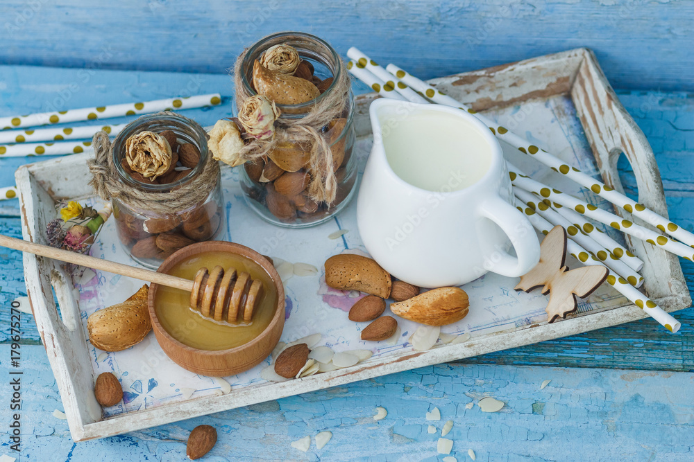 Honey in the wooden bowl, almonds and jar with milk on the wooden tray Honey in the wooden bowl, almonds and jar with milk on the wooden tray