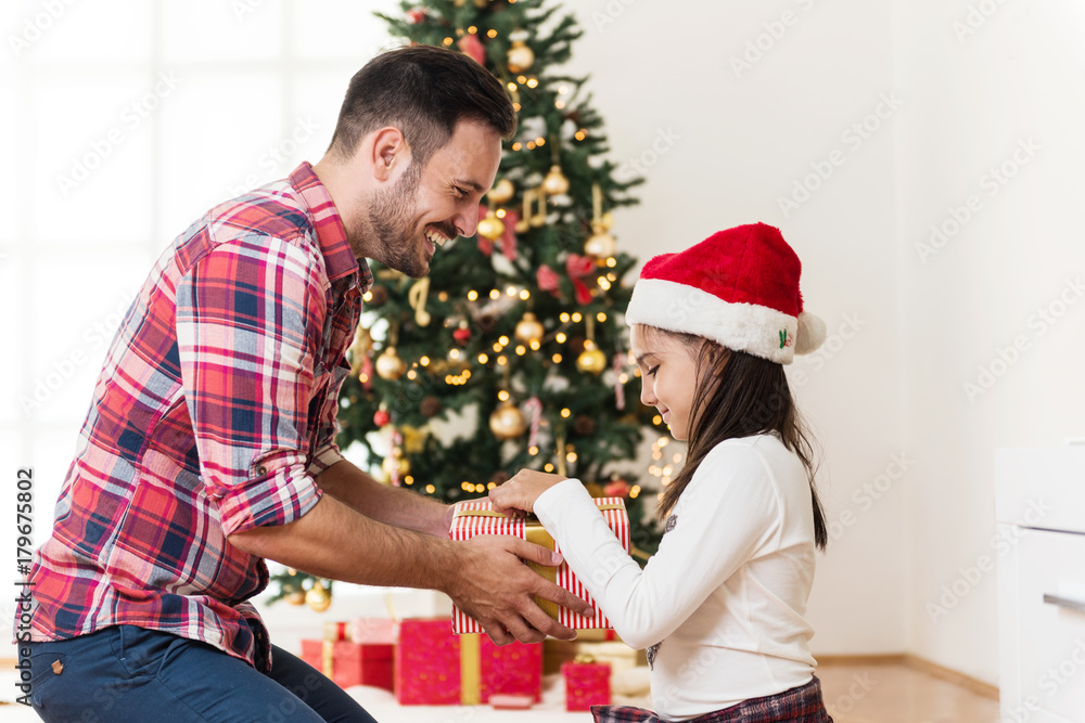 Father and daughter exchanging and opening Christmas presents