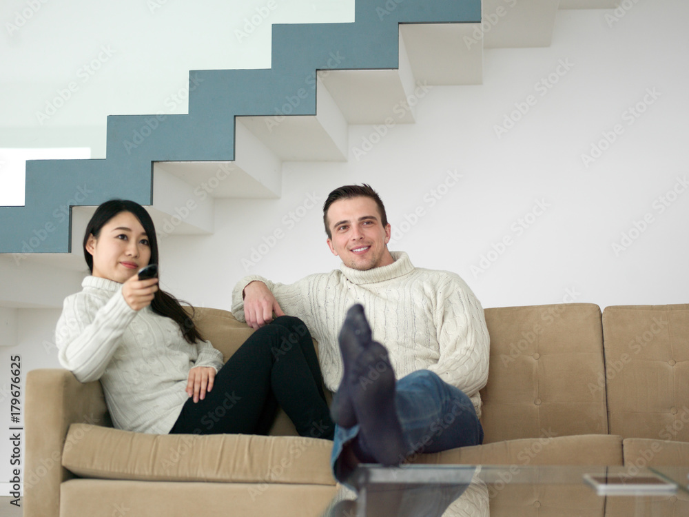 multiethnic couple on the sofa watching television multiethnic couple on the sofa watching television