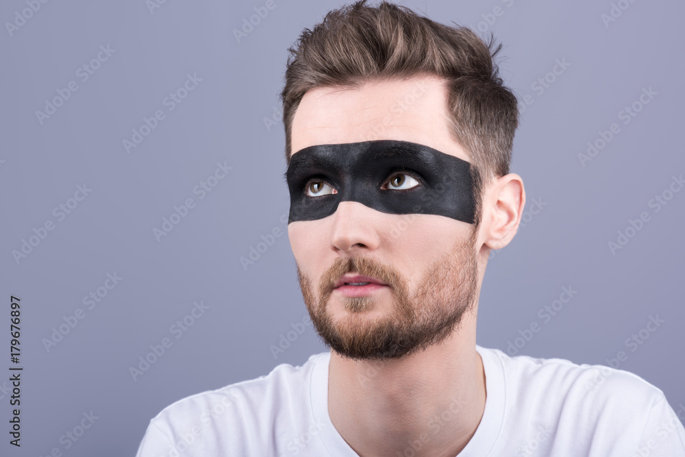 Fototapeta premium Beauty portrait of a man. A young man with a black strip on the eyes, makeup