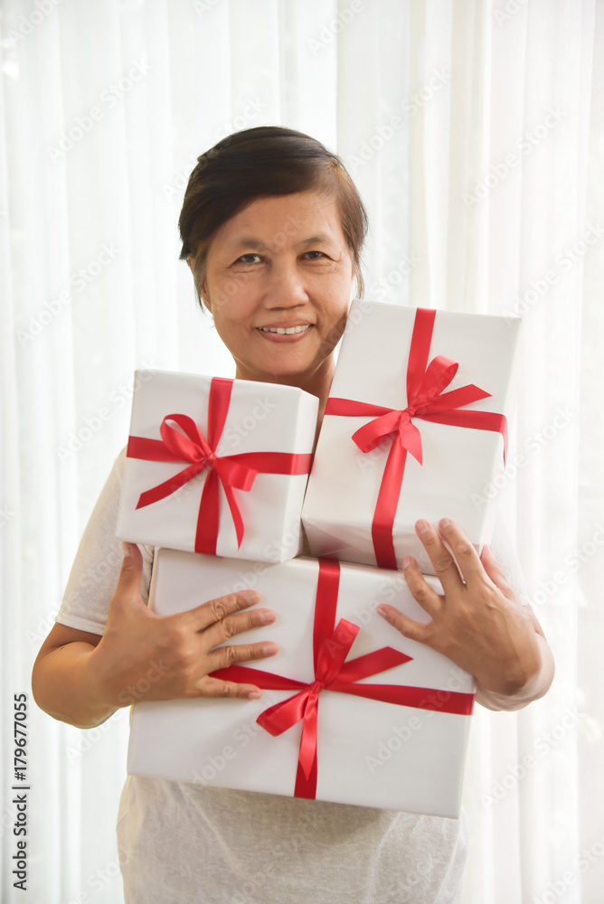 Asian elderly woman holding a white gift boxes. Asian elderly woman holding a white gift boxes.