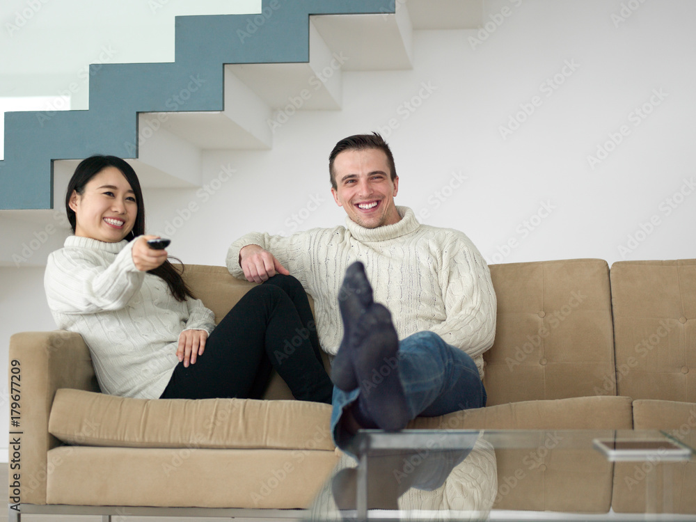 multiethnic couple on the sofa watching television multiethnic couple on the sofa watching television