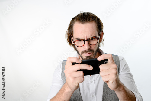 portrait of a 30 years old nerd geek playing game app on a smartphone isolated on white background © W PRODUCTION