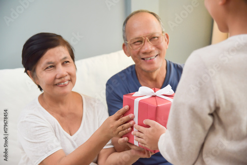 Grandfather and Grandmother receiving red gift box.