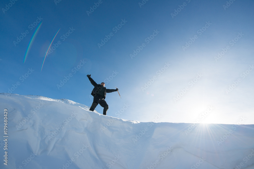 Happy climber with an ice ax in the snowy mountains Happy climber with an ice ax in the snowy mountains